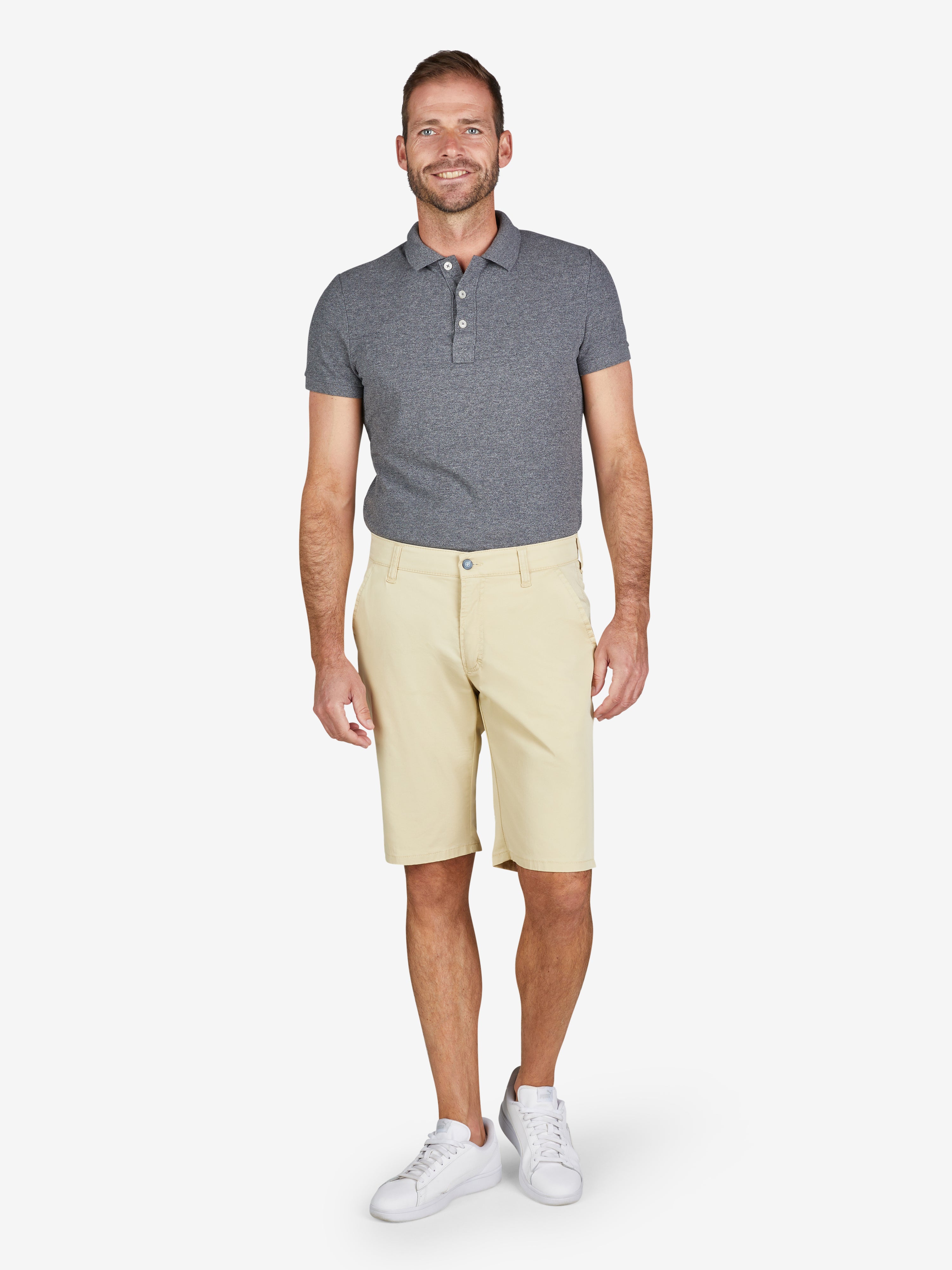Mann trägt helle Bermuda-Shorts ESPANA 8109 in Gelb mit elastischem Comfortbund, Hemdenstopper und High Stretch-Baumwoll-Mix. Kombiniert mit grauem Polo-Shirt, weißen Sneakers, frontal fotografiert.