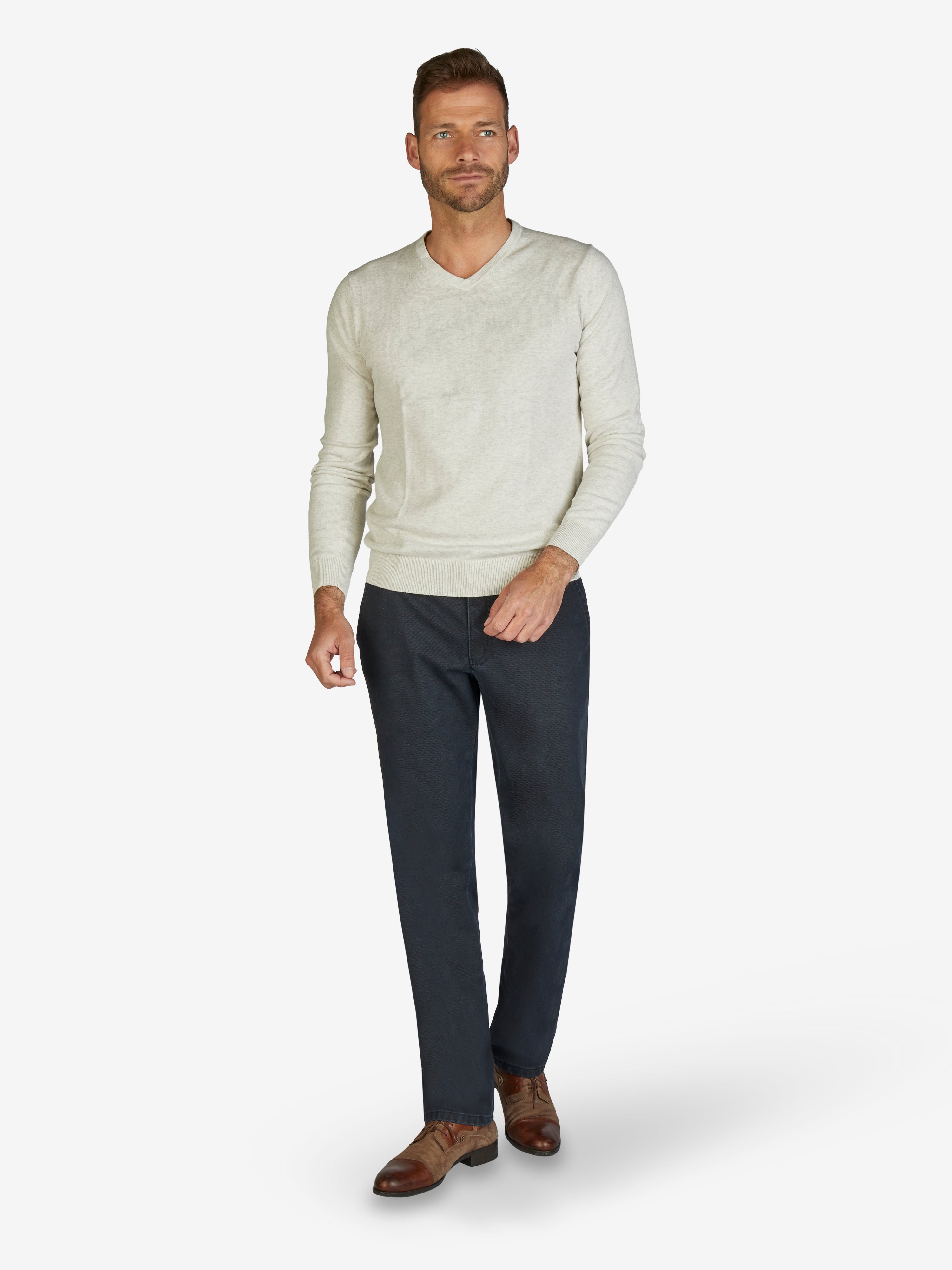 Mann trägt eine dunkelblaue GARVEY 7824 Flat Front-Hose mit Komfortbund, Hemdenstopper und Münztasche, kombiniert mit einem hellen Pullover und braunen Lederschuhen. Die Hose besteht aus Baumwolle mit Thermolite-Wärmeisolierung, geeignet für Herbst und Winter, regular fit, schmale Fußweite.