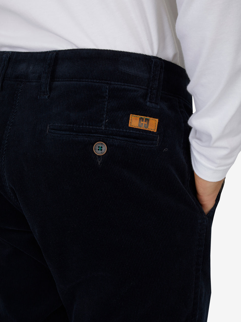 Nahaufnahme einer schwarzen Cord-Hose mit elastischem Komfortbund, Hemdenstopper und Knopf, getragen von einer Person in weißem Hemd, Produktmarkierung "GARVEY 8200" sichtbar.