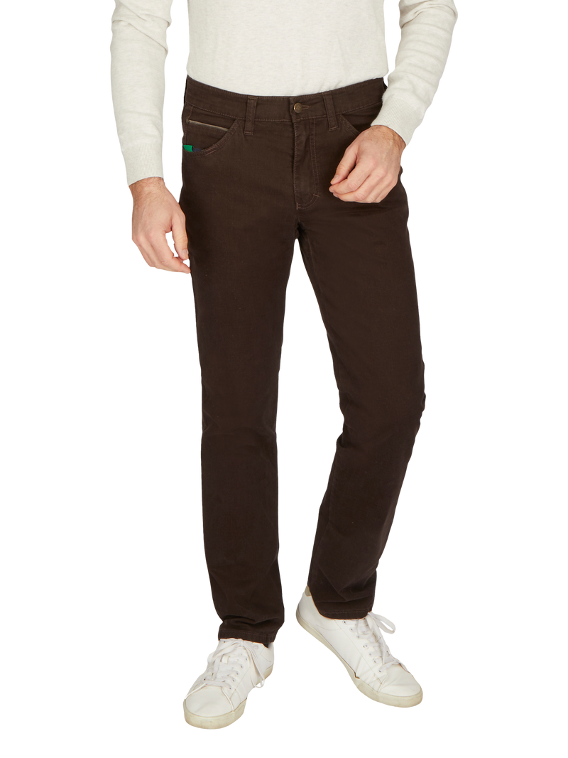 Elegante braune Herrenhose aus Baumwolle, mit Gürtelschlaufen, seitlichen Einschubtaschen und Gürtelschlaufen, kombiniert mit weißen Sneakers und einem hellen Pullover, Frontansicht.