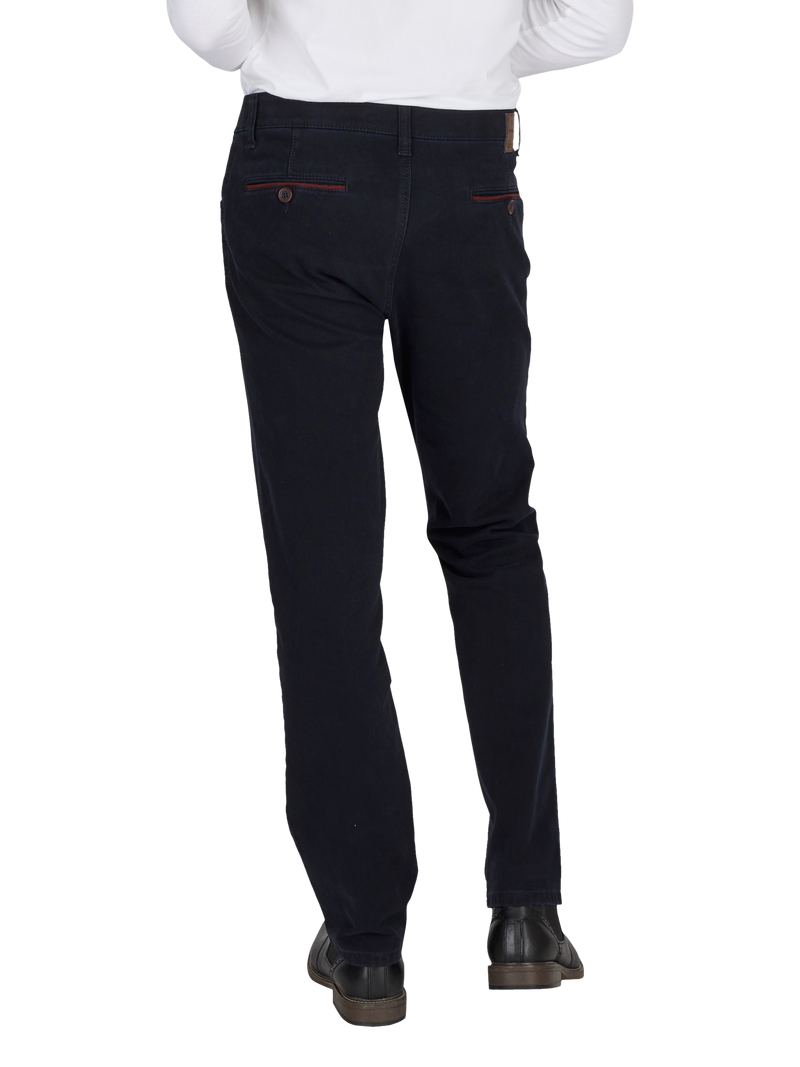 Hosenansicht einer Person, die dunkelblaue, gerade geschnittene Stoffhose trägt. Die Hose hat rote Kontrastnähte an den Taschen und einen hohen Bund. Die Person trägt eine weiße Oberbekleidung und schwarze Schuhe.