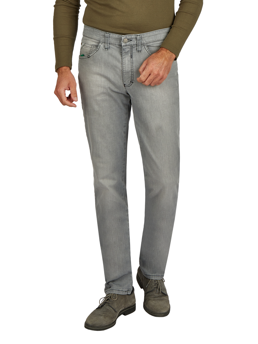 Der Bild zeigt einen Mann in einer grünen langärmligen Oberbekleidung und hellgrauen Jeans. Er steht mit einer Hand in der Hosentasche und trägt braune Schuhe. Das Bild fokussiert auf den unteren Bereich des Körpers.