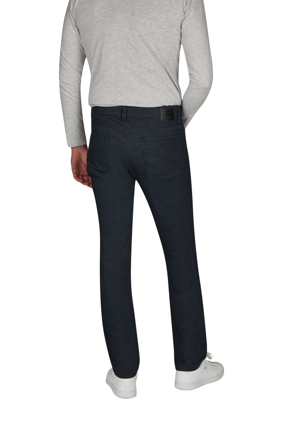 Ein Mann steht mit Rückenansicht, trägt eine graue Longsleeve und dunkle Jeanshose, kombiniert mit weißen Sneakers.