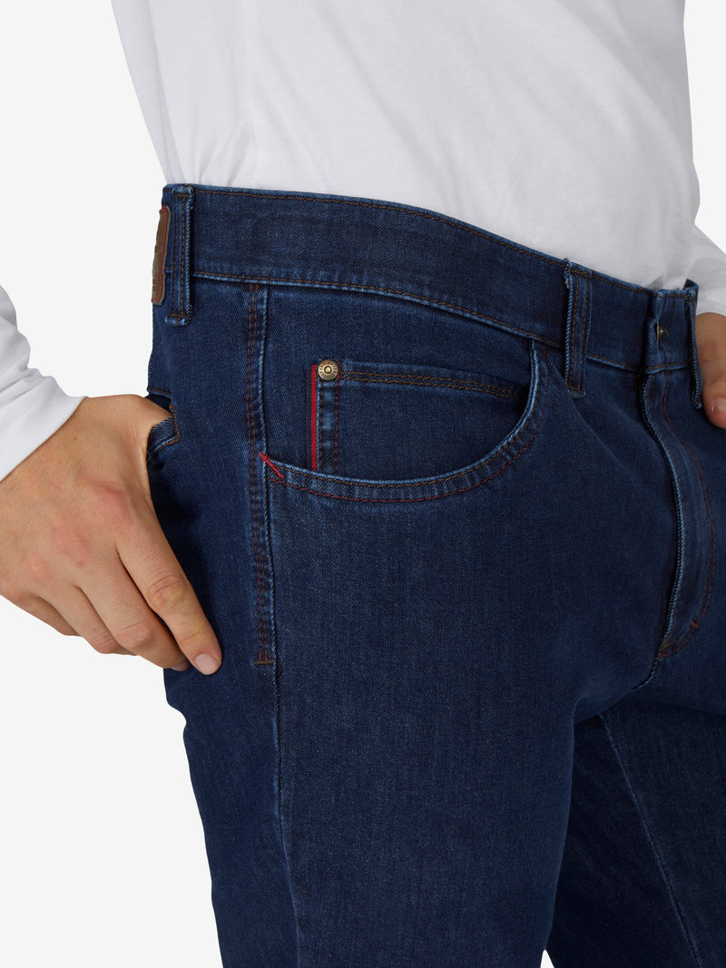 Nahaufnahme einer Person in jeansblauer Hose „MARVIN 7054“ von Club of Comfort, mit elastischem Komfortbund, Swing-Pocket, modifizierte 5-Pocket-Form, Regular Fit, aus hochelastischem Bi-Stretch-Denim mit T400-Beimischung, formstabil, kurz, ganzjährig, blaue Farbfamilie.